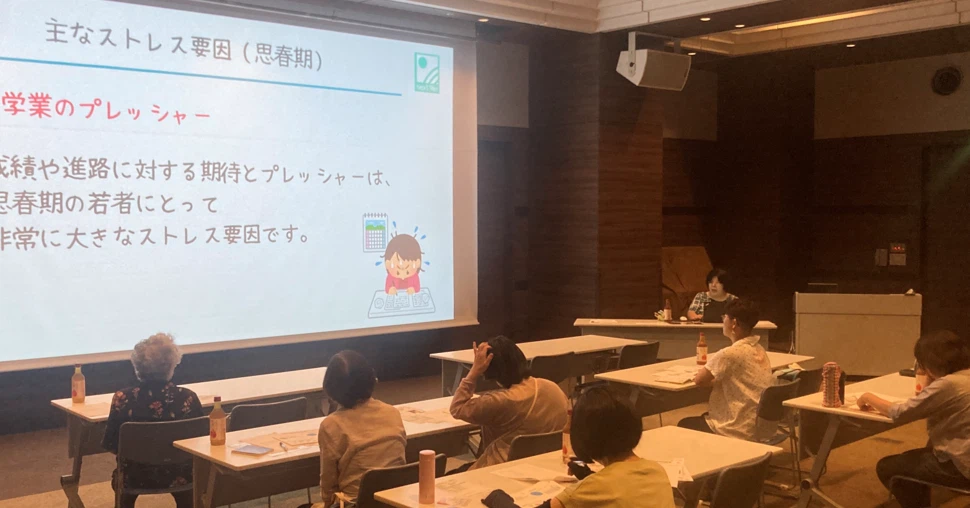 スクリーンを使った講演会場で参加者に話す眞島香奈子