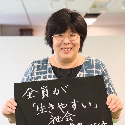 「全員が生きやすい社会」と書かれた黒板を持つ眞島香奈子